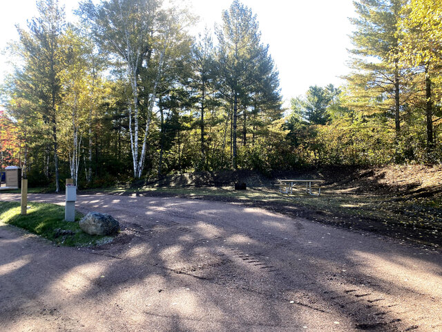 A picture of one of the RV sites at the Babbitt Campground and RV Park. It has full hookups and a table.