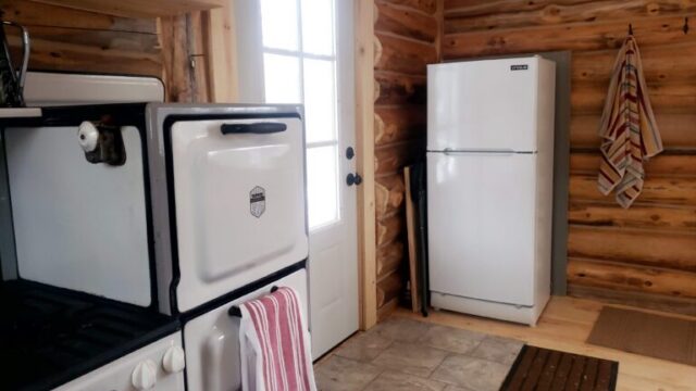 A view of the kitchen in the Bucksnort cabin. It has a small stove, oven, and refrigerator.