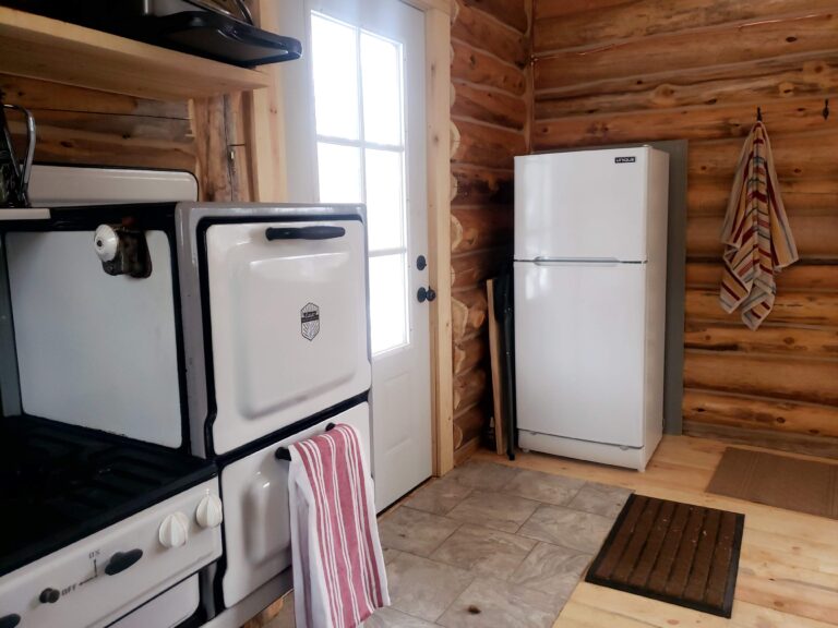 A view of the kitchen in the Bucksnort cabin. It has a small stove, oven, and refrigerator.