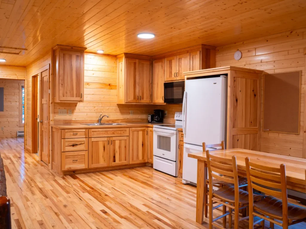 An inside view of the Castillo cabin's kitchen. It has a refrigerator, long table, microwave, stove, and coffee pot.