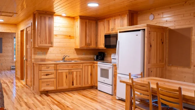 An inside view of the Castillo cabin's kitchen. It has a refrigerator, long table, microwave, stove, and coffee pot.