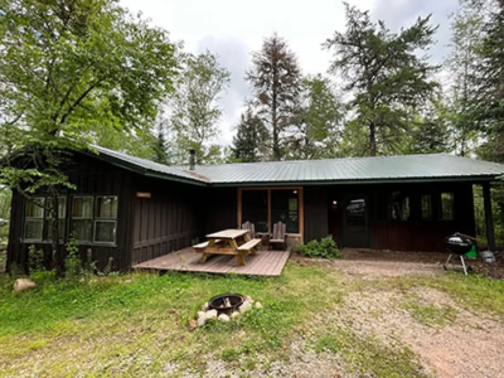 An outside view of the Castillo cabin. It has a picnic , and charcoal grill.