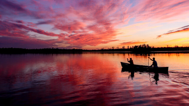A canoe on the lake with a sunset at Camp Voyageur