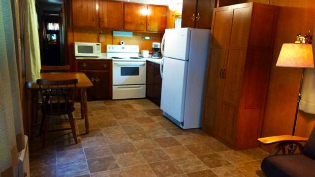 The kitchen of one of the cabins at Canoe Country Cabins. It has a refrigerator, stove, oven, microwave, coffee pot, and small table.