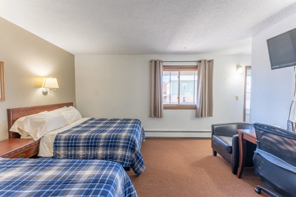 One of the two queen rooms at Canoe on Inn. It has two queen beds, lamps, a television and a chair.