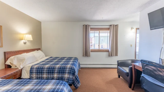 One of the two queen rooms at Canoe on Inn. It has two queen beds, lamps, a television and a chair.