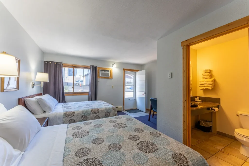 One of the two queen rooms at Canoe on Inn. It has two queen beds, lamps, and a chair.