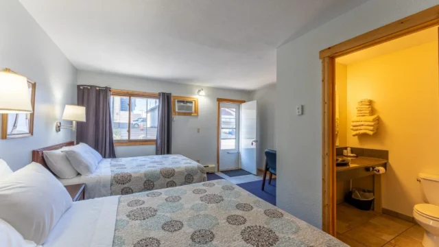 One of the two queen rooms at Canoe on Inn. It has two queen beds, lamps, and a chair.