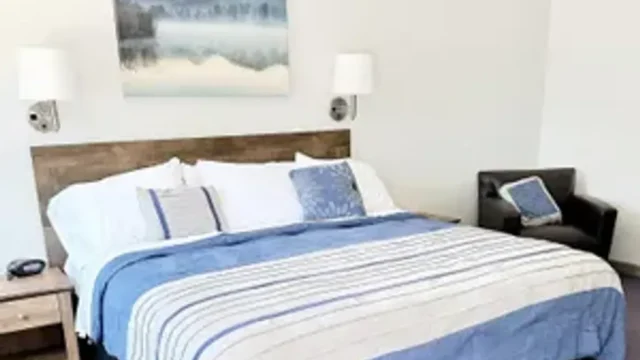 One of the single bed rooms at Canoe on Inn. It has the bed, a night stand, a chair, and lamps.