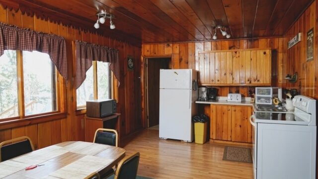 A view of the kitchen and dining area of the Cedar cabin at Shagawa Beach Cabins. It has a table, a refrigerator, stove, and oven.