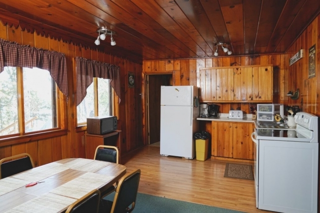 A view of the kitchen and dining area of the Cedar cabin at Shagawa Beach Cabins. It has a table, a refrigerator, stove, and oven.