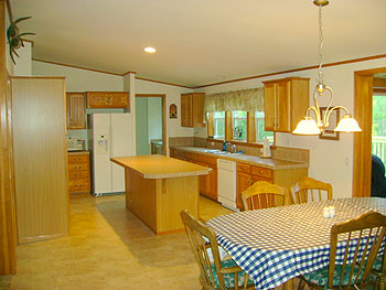 The kitchen of one of the cabins at Echo Shores Resort. It has a kitchen island, table, refrigerator, and dishwasher.