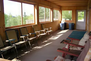 A screened in porch for one of the cabins at La Tourell's. It has chairs for sitting and enjoying the weather.