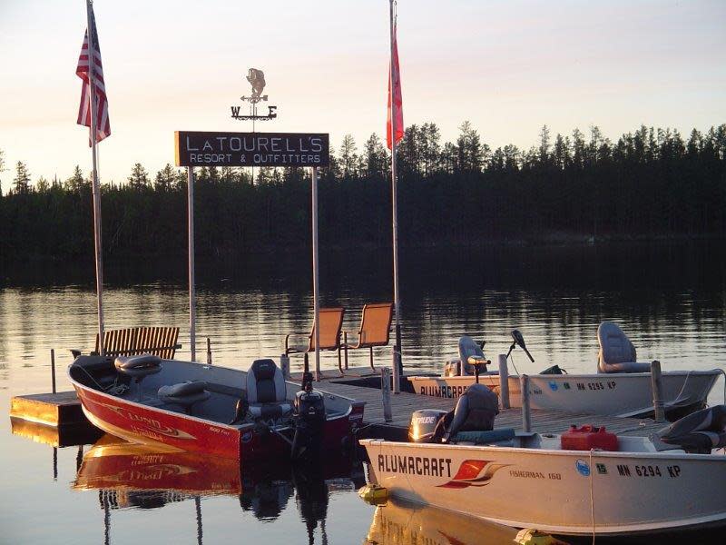 A picture of one of the docks at LaTourell's Resort. There are three boats in water.