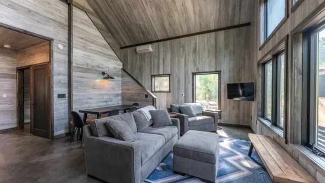 The inside of one of the cabins at the North of North Resort with two couches facing large windows with sun shining in the room.