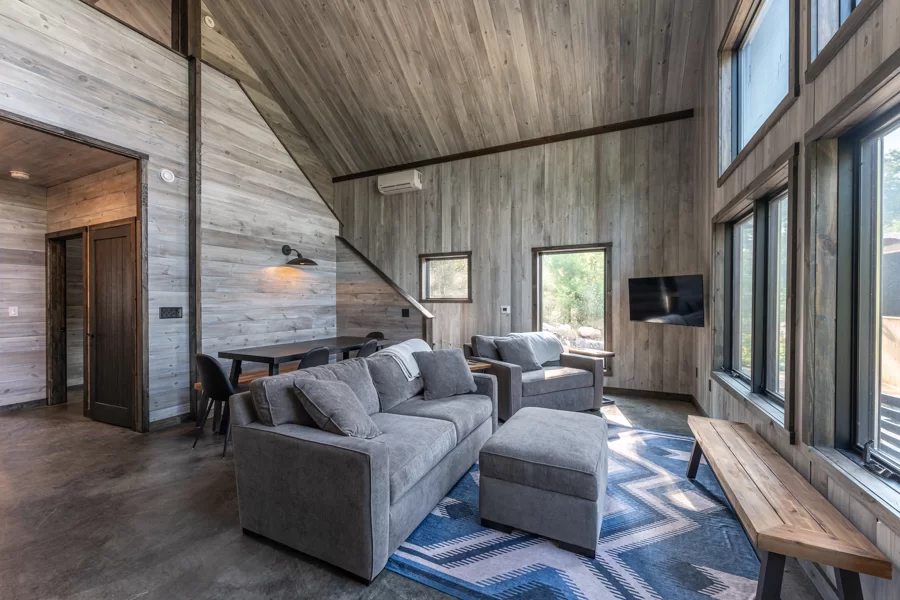 The inside of one of the cabins at the North of North Resort with two couches facing large windows with sun shining in the room.