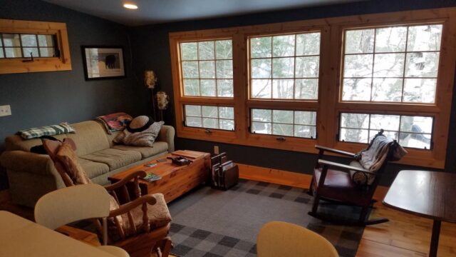 The inside of a cabin at Shagawa Beach Cabins. It has large windows a couch and a rocking chair.