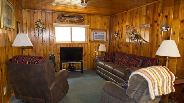 The relaxing area in the Spruce cabin at the Shagawa Beach Cabins. It has two recliners, a couch, a television, and several lamps.