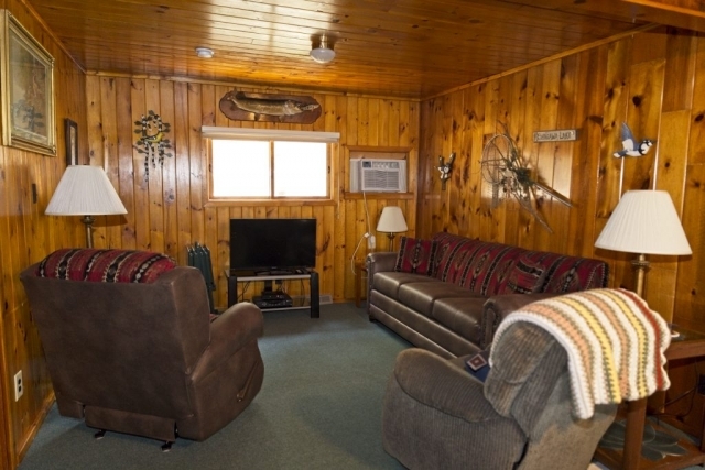 The relaxing area in the Spruce cabin at the Shagawa Beach Cabins. It has two recliners, a couch, a television, and several lamps.