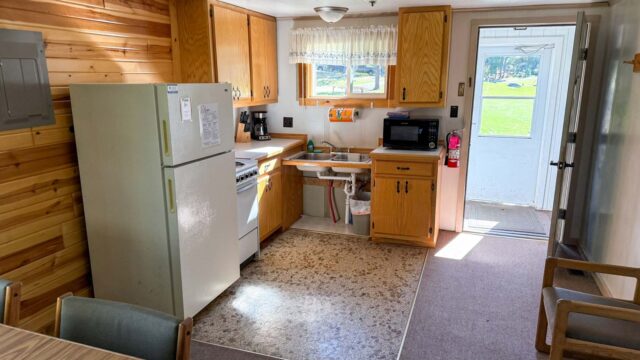 The kitchen of one of the two bedroom cabins at Veterans on the Lake Resort. It has a refrigerator, stove, oven, microwave, and coffee pot.